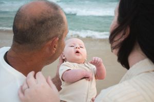 Newcastle newborn baby photographer capturing new father and mother holding baby at the beach