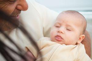 Newcastle newborn baby photographer capturing new father holding baby at the beach