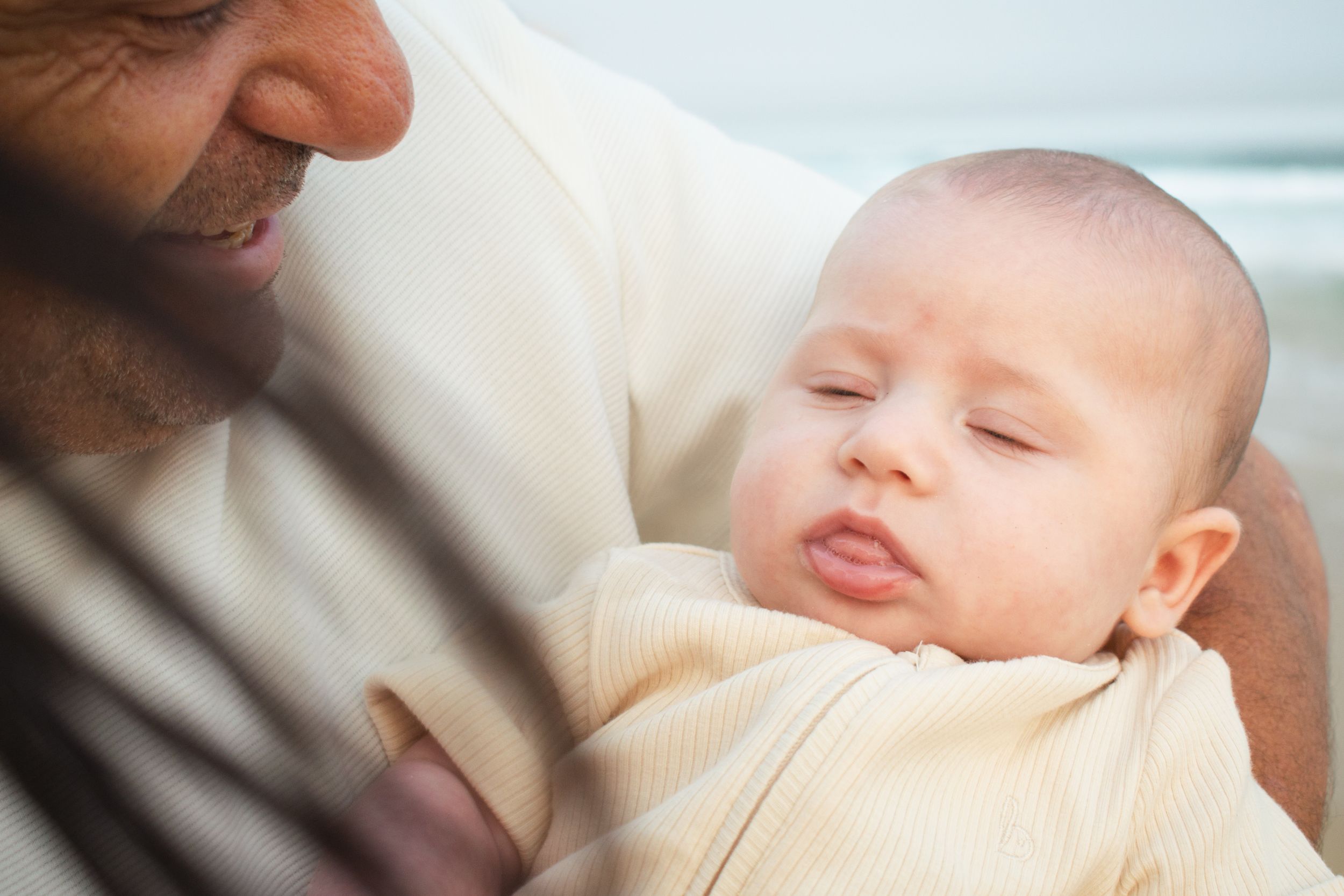 Newcastle newborn baby photographer capturing new father holding baby at the beach