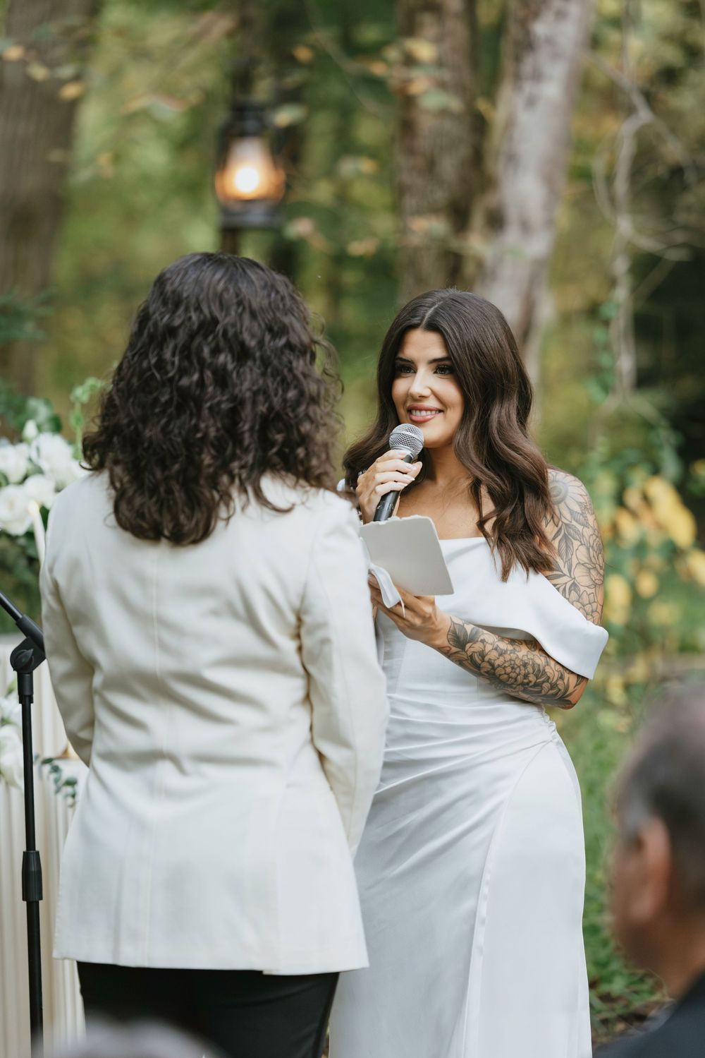 Two people exchange vows during an intimate outdoor wedding ceremony in a lush forest setting.