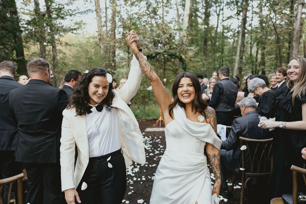 Wedding guests dance and celebrate together on an outdoor dance floor surrounded by trees during a forest reception.