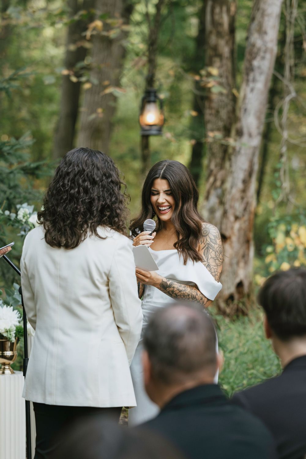 Couple sharing joyful moments during outdoor wedding ceremony in a lush forest setting.