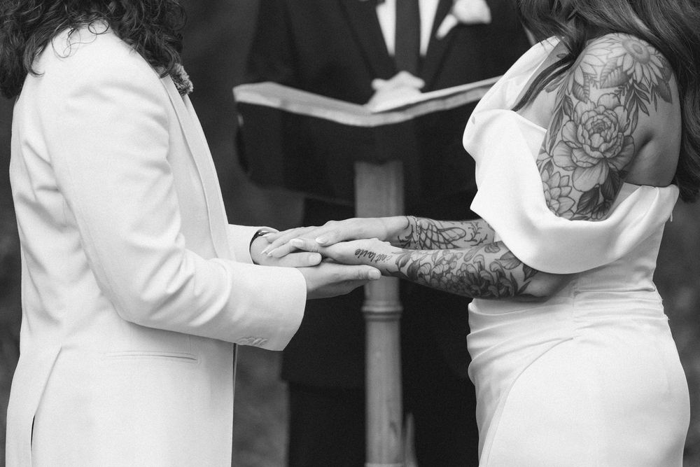 Wedding party members in black and white attire embrace and celebrate during an outdoor ceremony.
