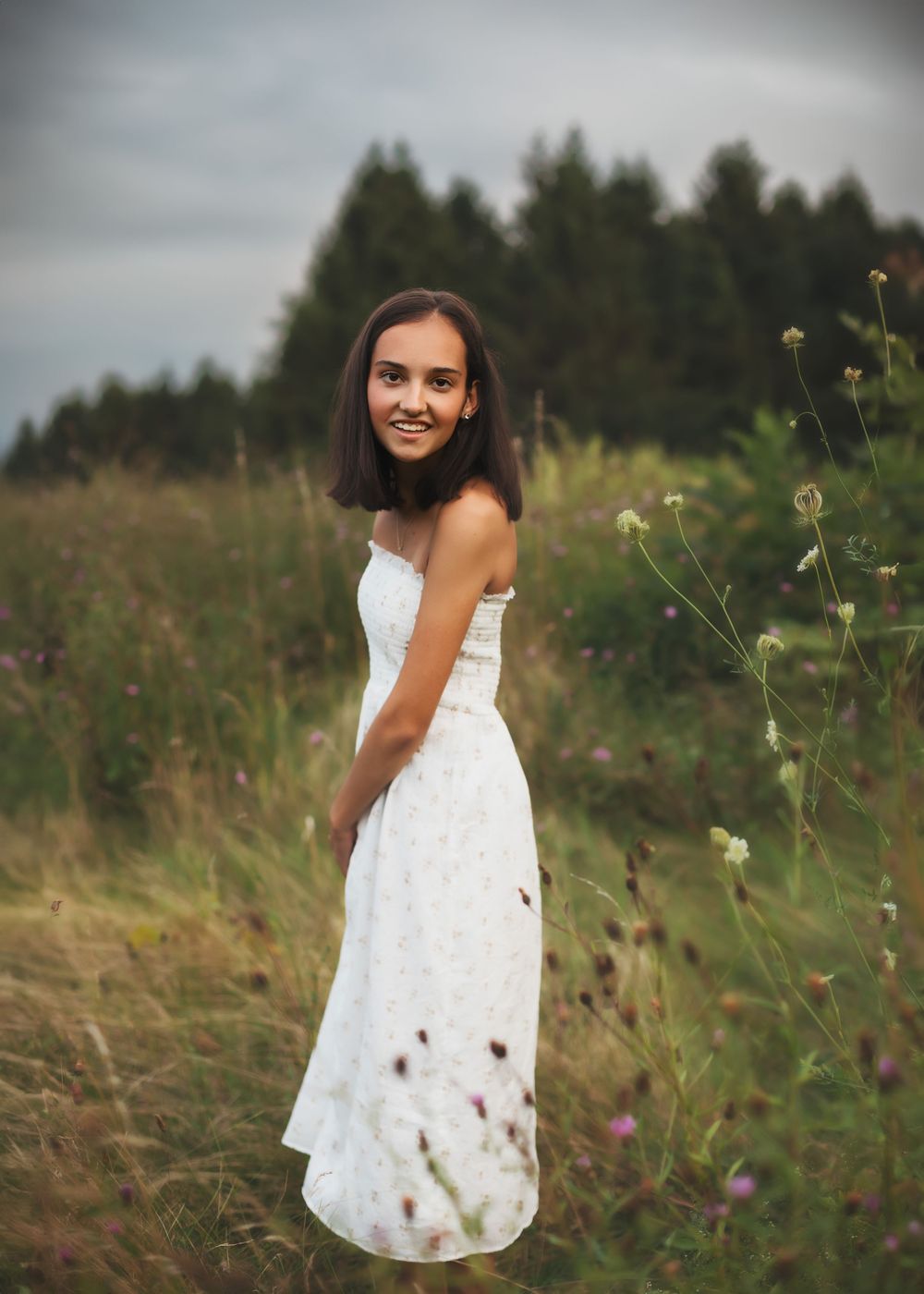 A white sundress twirls in a summer meadow with wildflowers.