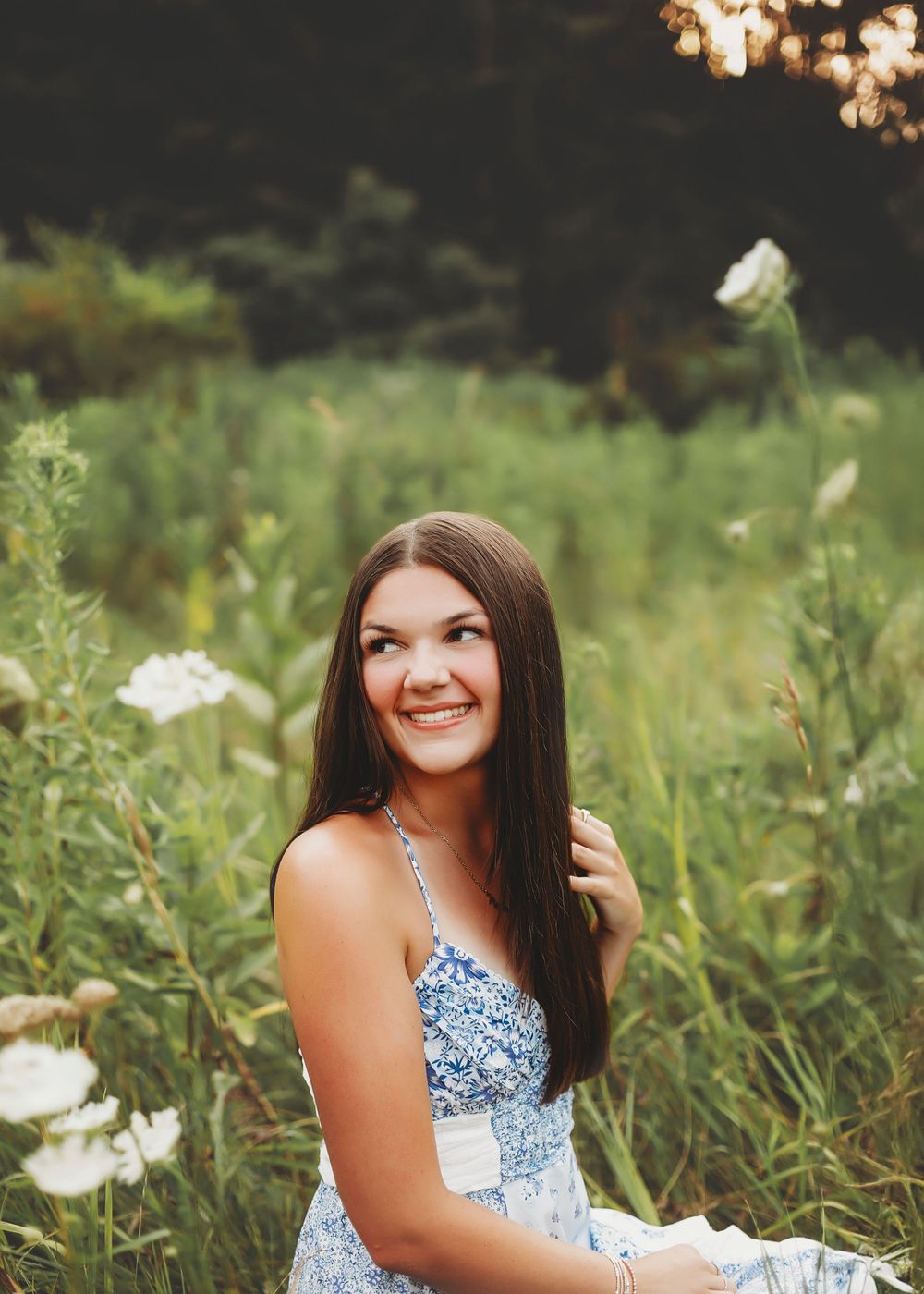 Portrait in a wildflower meadow featuring someone in a blue floral dress during golden hour.