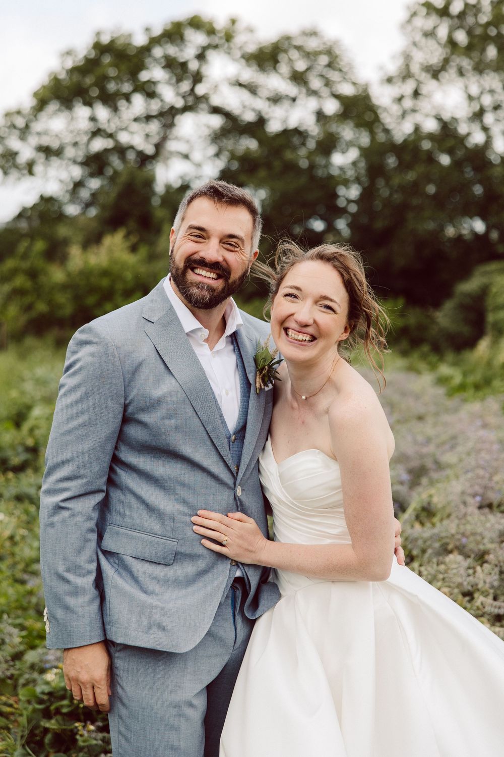A happy couple shares joyful moments together during their outdoor wedding photoshoot in a scenic natural setting.