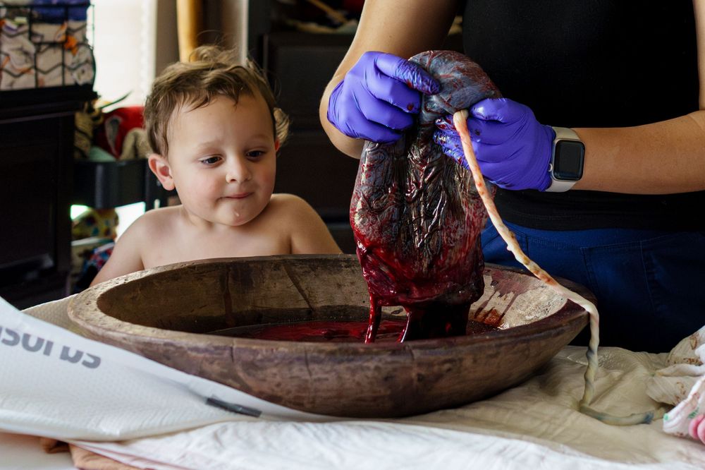 Close up view of hands working with chocolate in a rustic wooden bowl during a culinary demonstration.