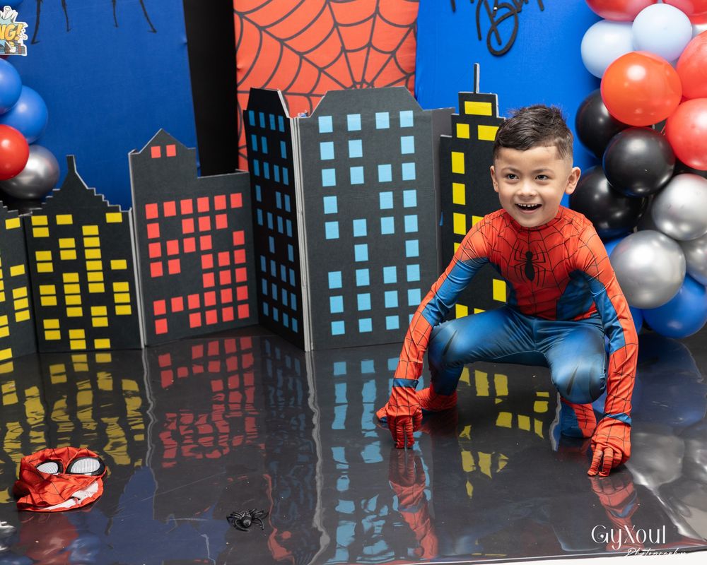 Spider-Man figure stands against a cityscape backdrop with red and black balloons and spider web decorations.