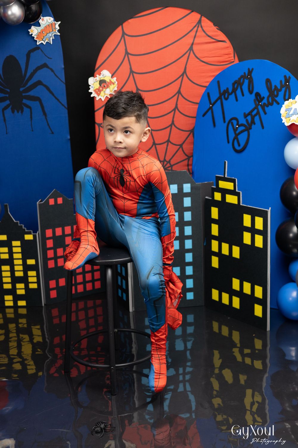 Superhero-themed photo backdrop with city skyline silhouette featuring blue and red colors against a dark background.