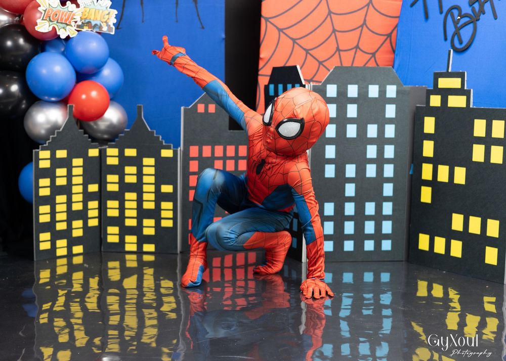 A sequence of Spider-Man action figures posed against a cityscape backdrop with illuminated buildings at night.
