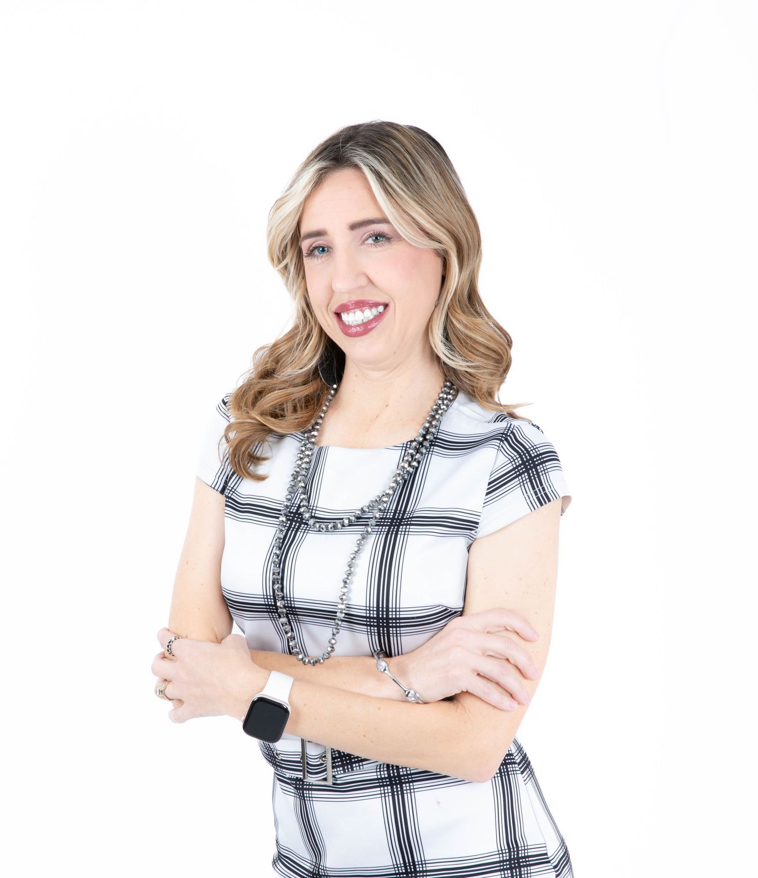 Professional portrait of someone wearing a black and white plaid short-sleeve top with arms crossed and a warm smile.
