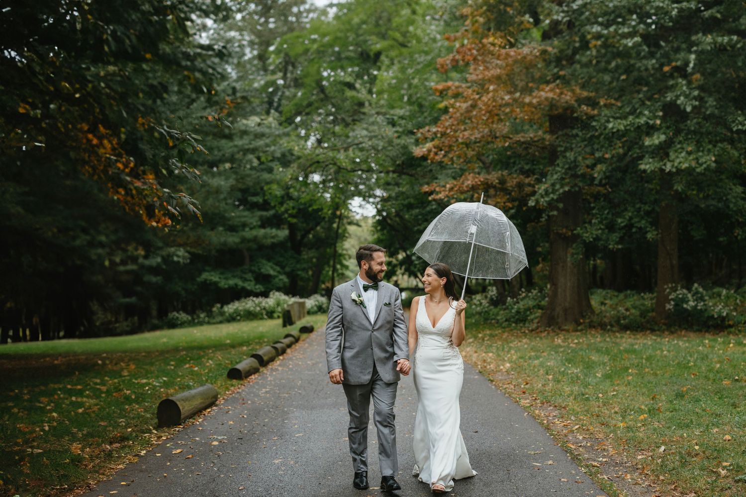 Smiling wedding couple with an umbrella walking in the Hudson Valley