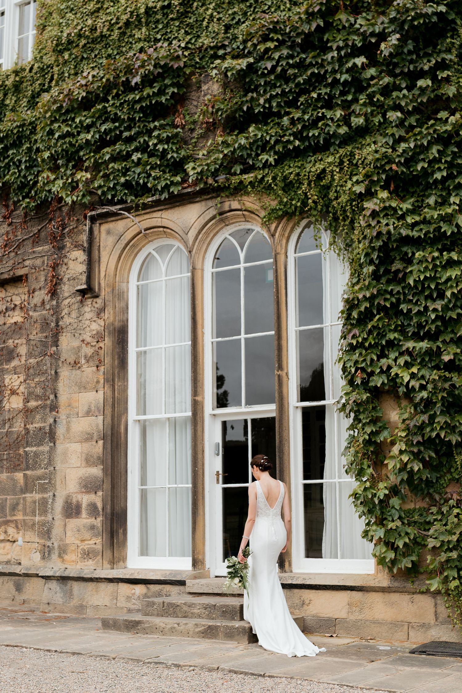 Wedding guests celebrate with confetti and bubbles as newlyweds exit their brick venue with joyful smiles.
