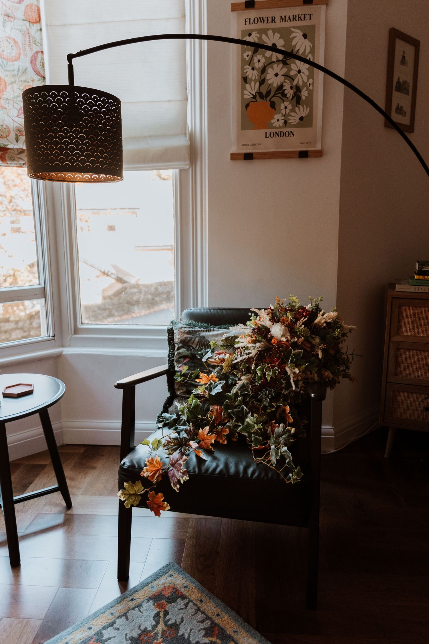 Modern dining room interior with dark wood table, black chairs and floral arrangements near bright windows.