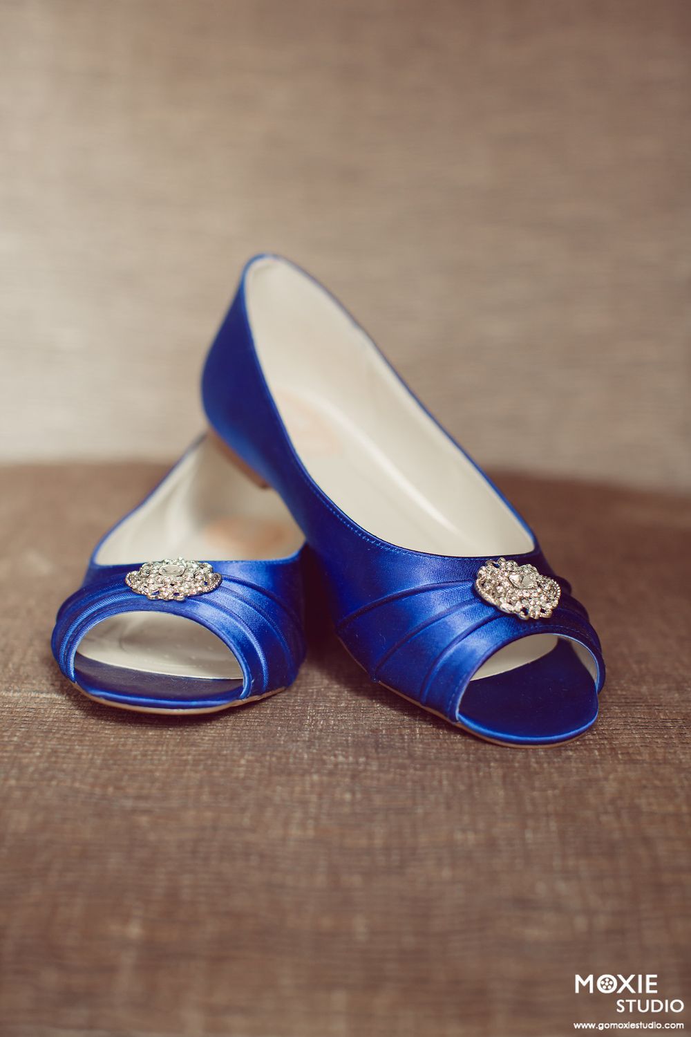 Royal blue satin peep-toe bridal shoes with crystal embellishments photographed in sequence on brown linen fabric.