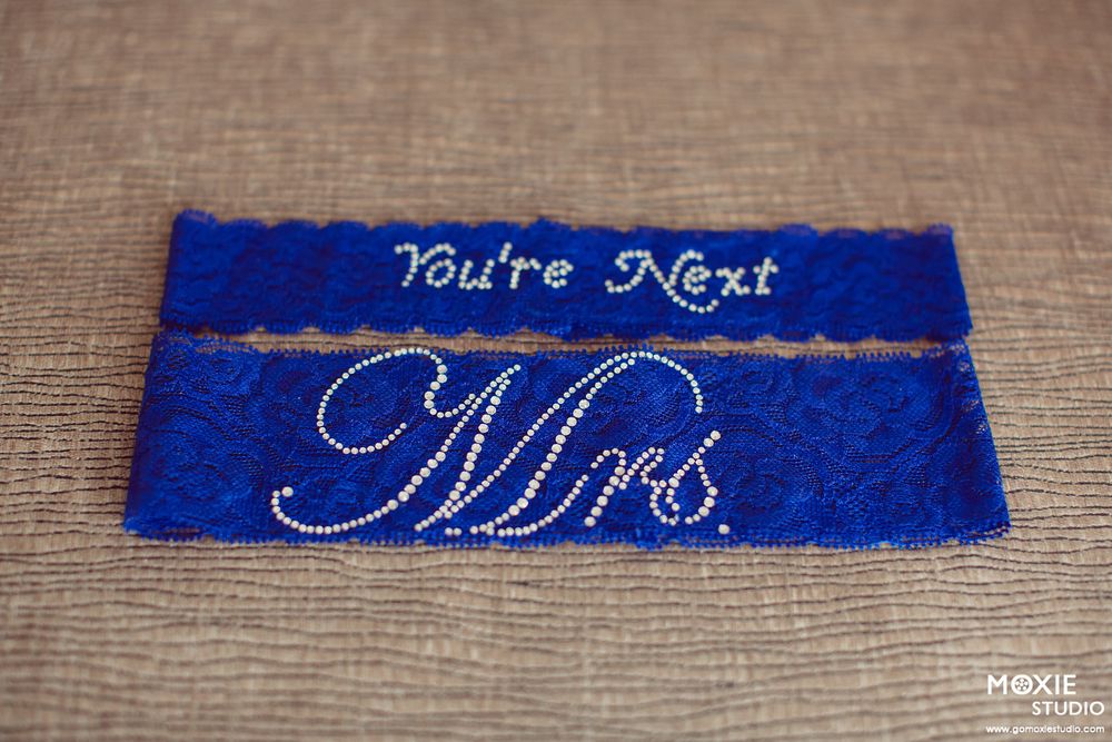 Decorative blue ribbon pieces with white embroidered text spelling out 'You're Next' and 'Mrs' on a textured fabric background.