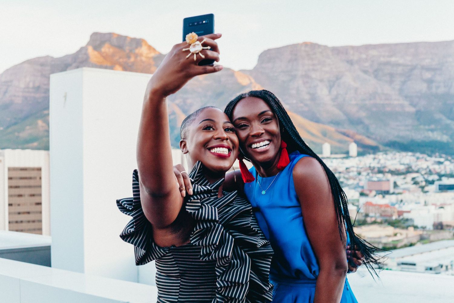 Happy couple taking selfies against mountain landscape backdrop.