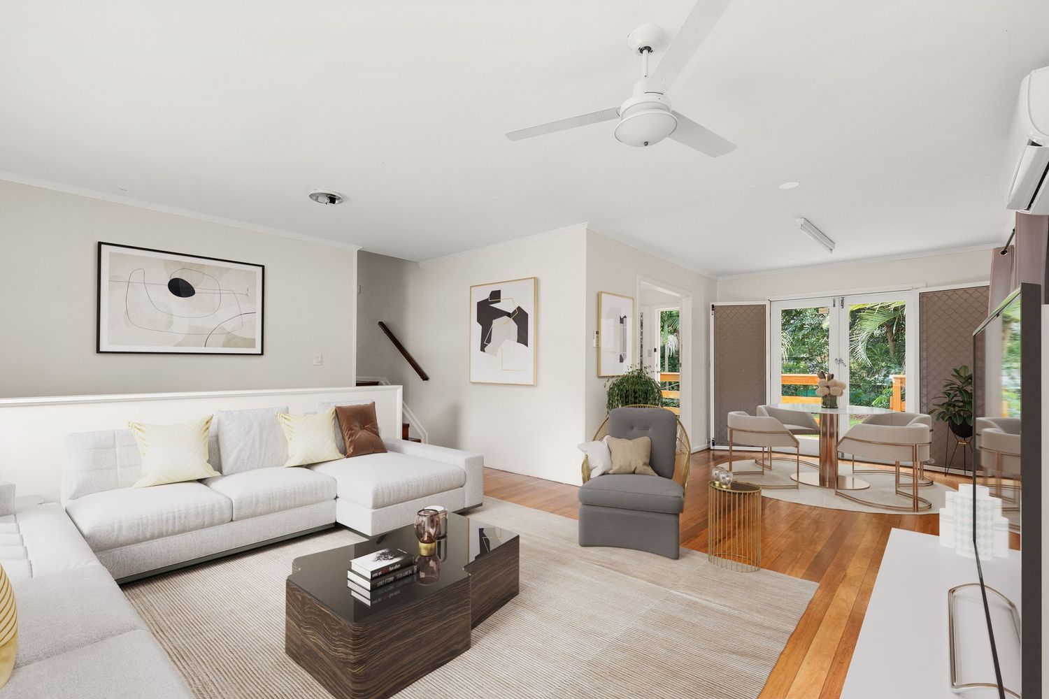 Bright open-plan living room with white sofas, ceiling fan, timber floors, and natural light flowing from adjacent dining area.