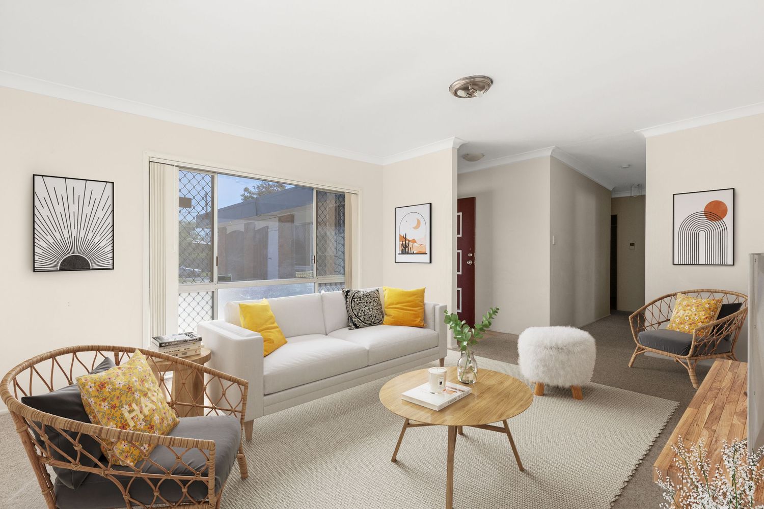 Light-filled living room with white sofa, rattan chairs, and neutral decor.