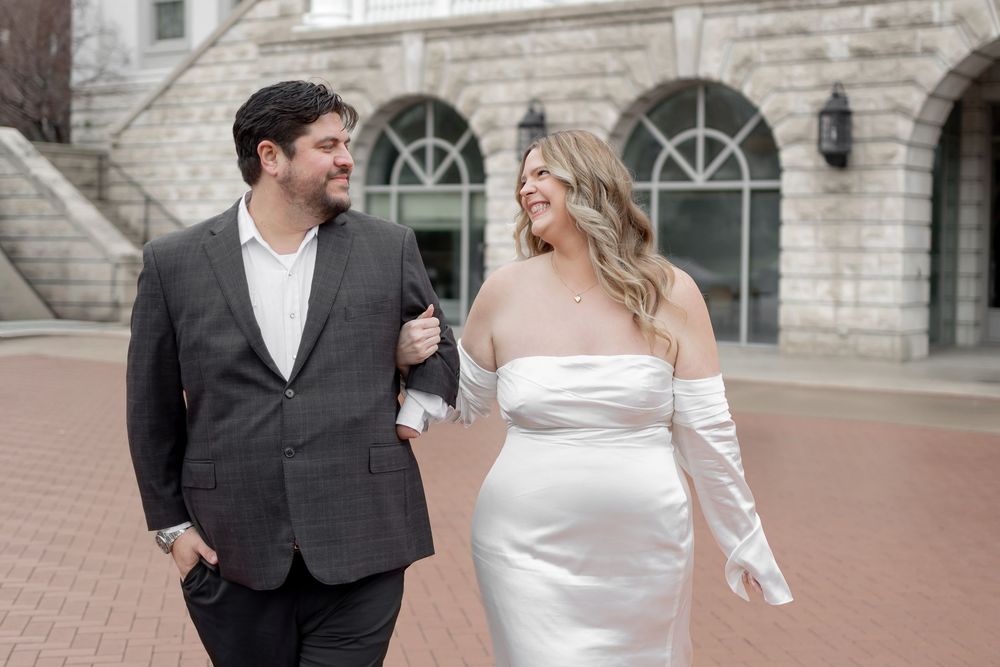 A couple shares a joyful moment together during their wedding celebration outside a grand stone building.