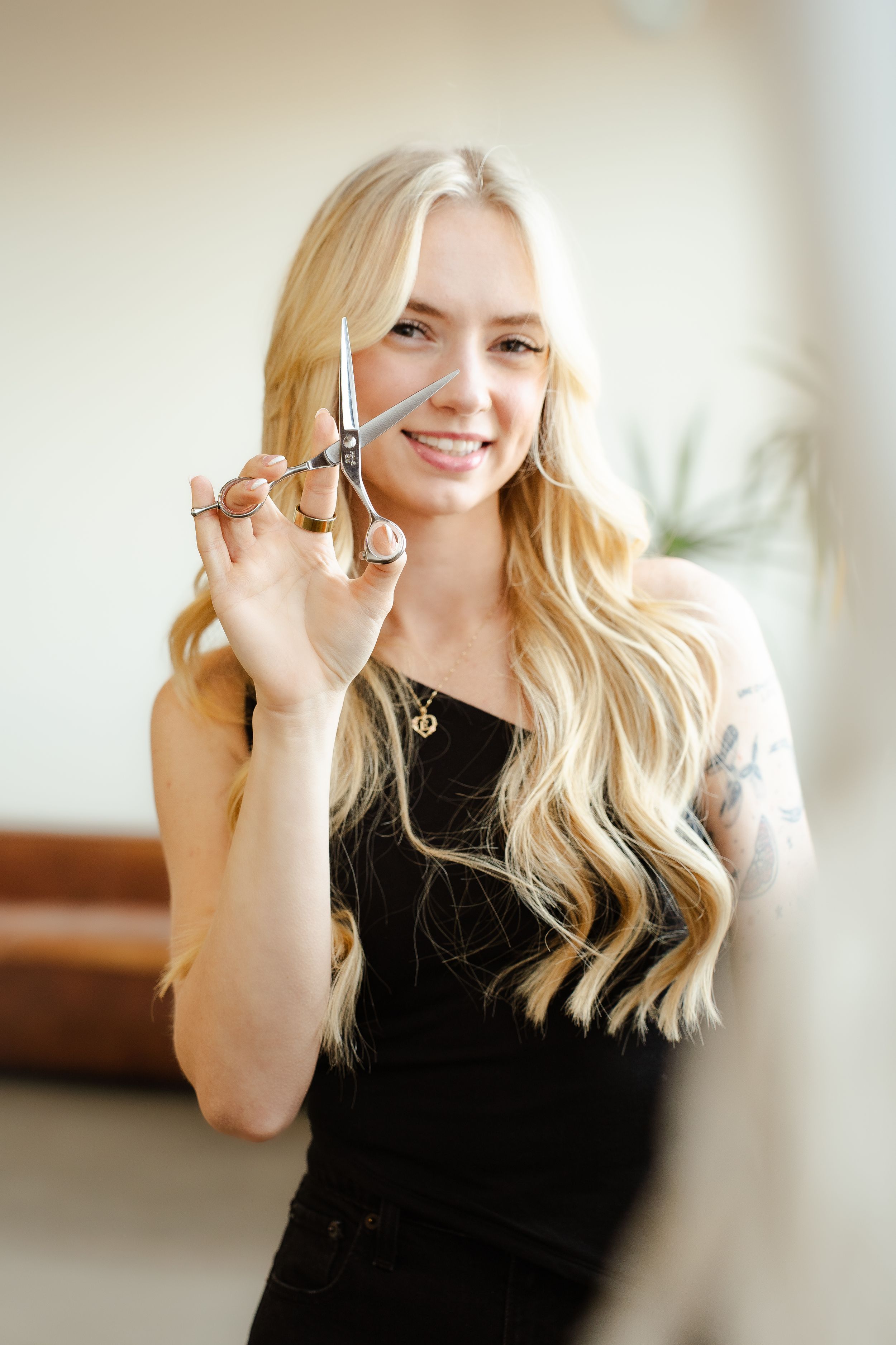 A person in a black top holds up a silver key while smiling against a bright background.