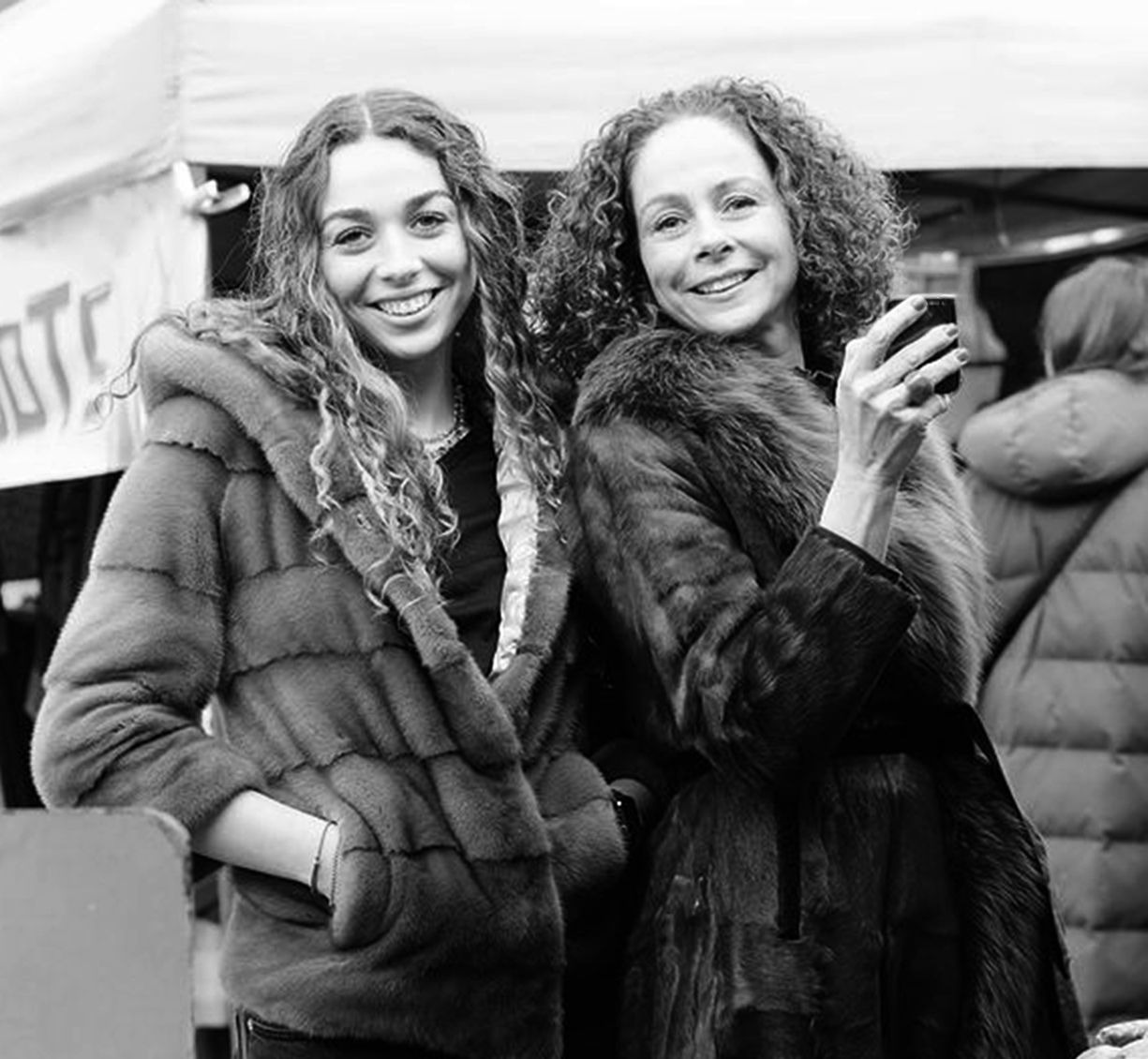 A series of black and white candid photos showing people laughing and smiling together outdoors in winter coats.