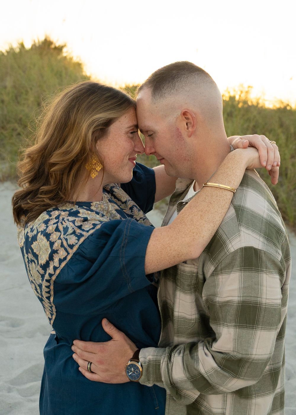 Romantic couple embraces on a beach at sunset, sharing tender moments in a series of intimate photos.