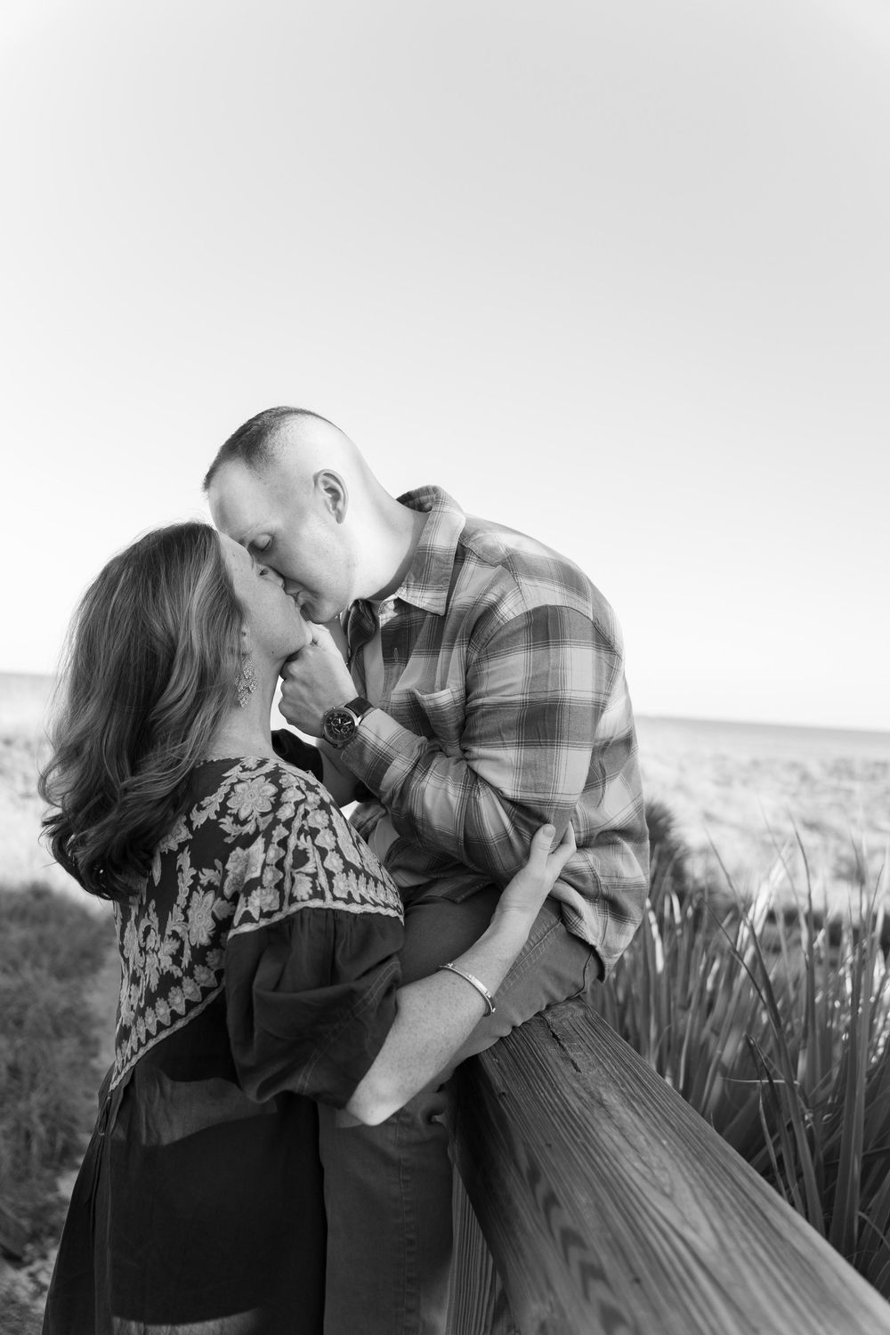 A romantic black and white photo of a couple sharing an intimate moment in an outdoor setting.