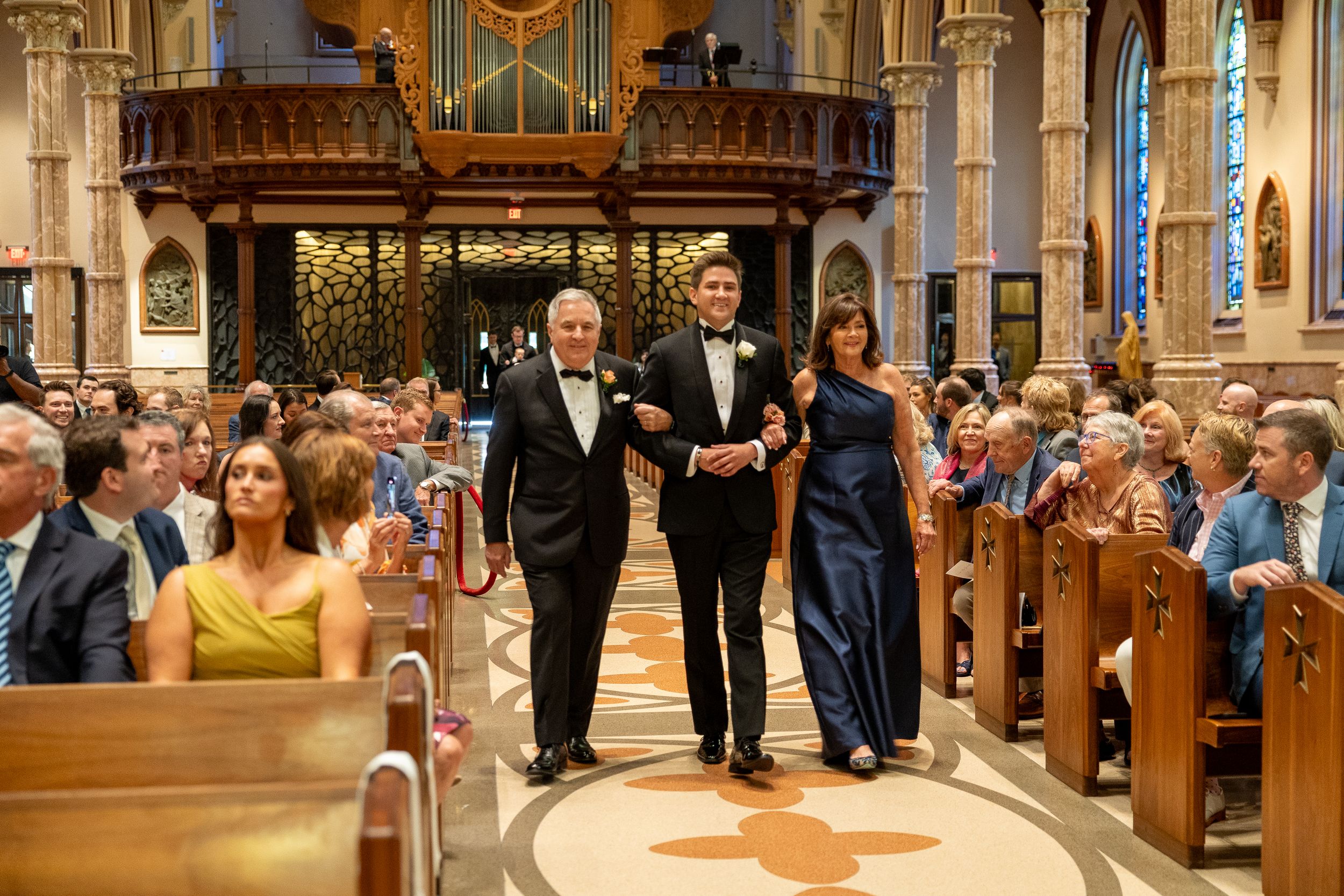 Wedding ceremony guests seated in church pews watching a traditional Catholic mass celebration.
