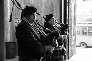 Musicians perform on stringed instruments in a black and white vintage scene.