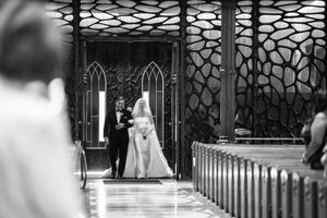Black and white photo of a church interior with geometric pattern windows and wooden pews.