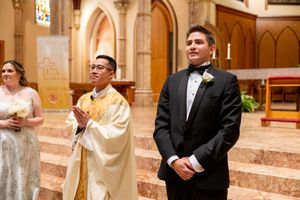 Traditional Catholic wedding ceremony taking place at ornate church altar with Gothic architecture details.