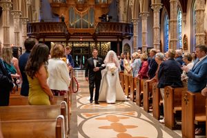 Wedding ceremony taking place in a beautiful historic church with ornate organ pipes and decorative interior details.