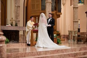 Wedding ceremony taking place in a grand cathedral with ornate Gothic architecture and stained glass windows.