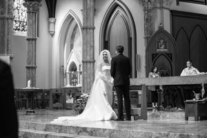 Black and white panoramic view of a traditional church wedding ceremony in a Gothic sanctuary.