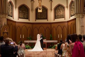A wedding ceremony takes place in a grand cathedral with ornate gothic architecture and stained glass windows.