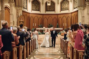 Wide angle view of a church wedding with guests seated in wooden pews beneath vaulted ceilings.