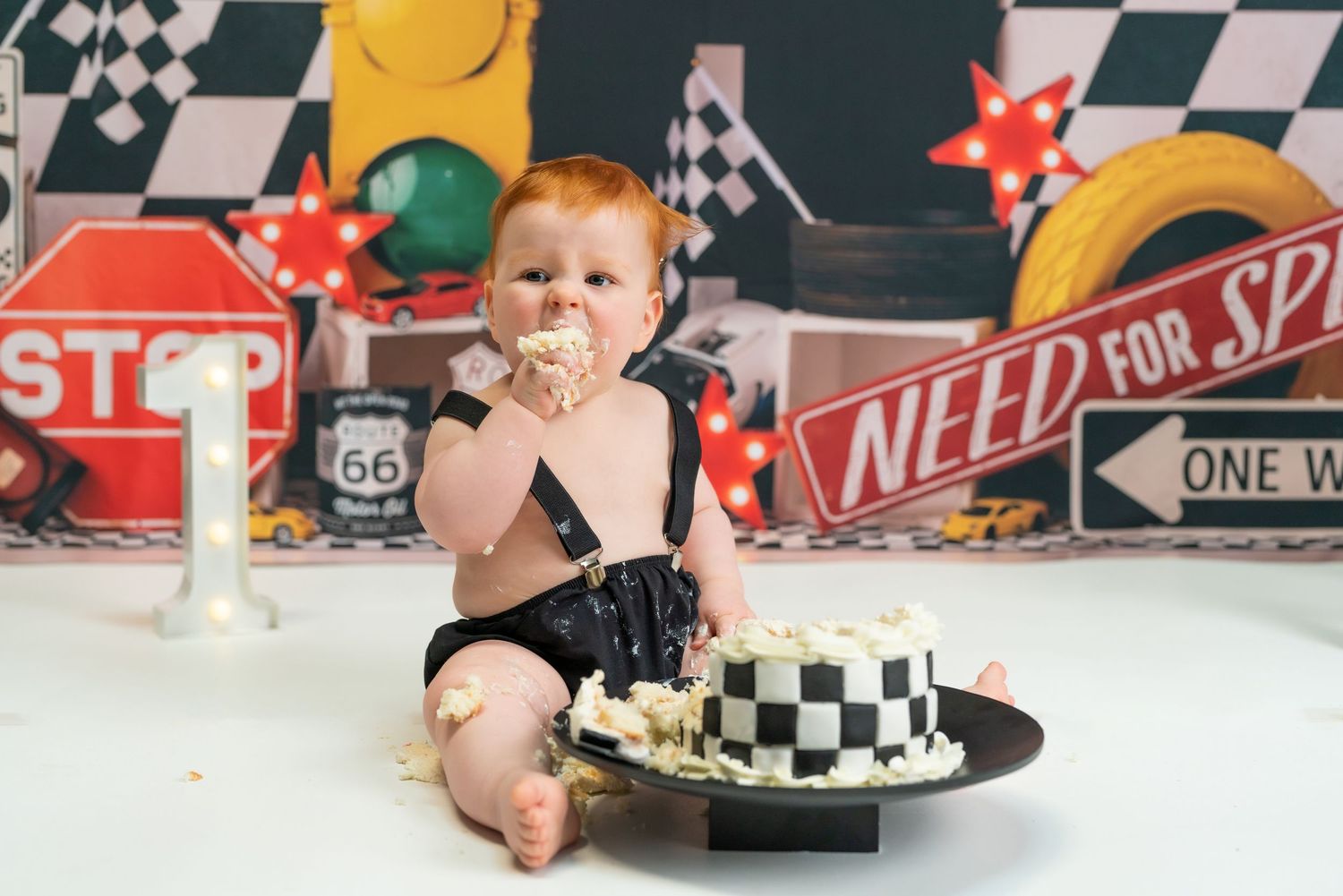 A checkered racing flag themed birthday party setup with cake and decorations for a first birthday celebration.