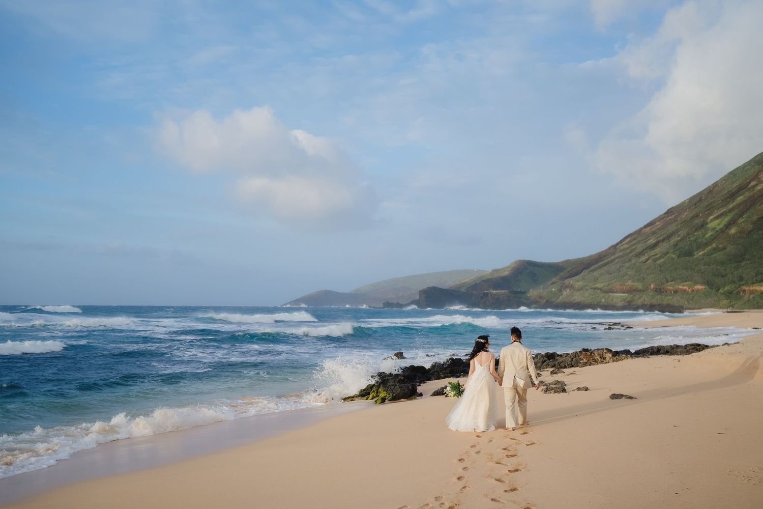 Panoramic view of a rugged coastline with waves crashing against rocky cliffs and sandy beaches under blue skies.