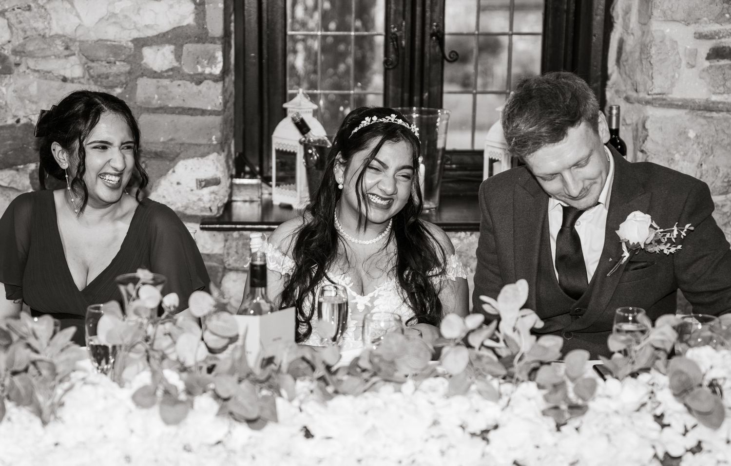 A black and white panoramic collage shows candid moments of celebration at a wedding reception with floral decorations.