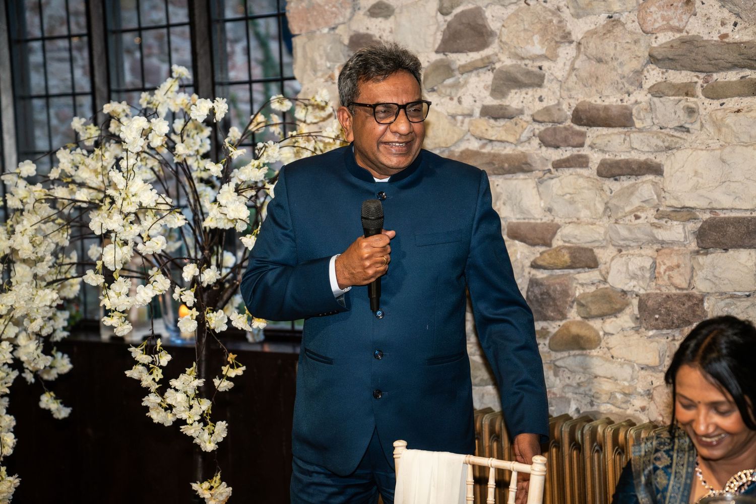 Wedding reception at rustic stone venue with floral decor and guests enjoying celebration.