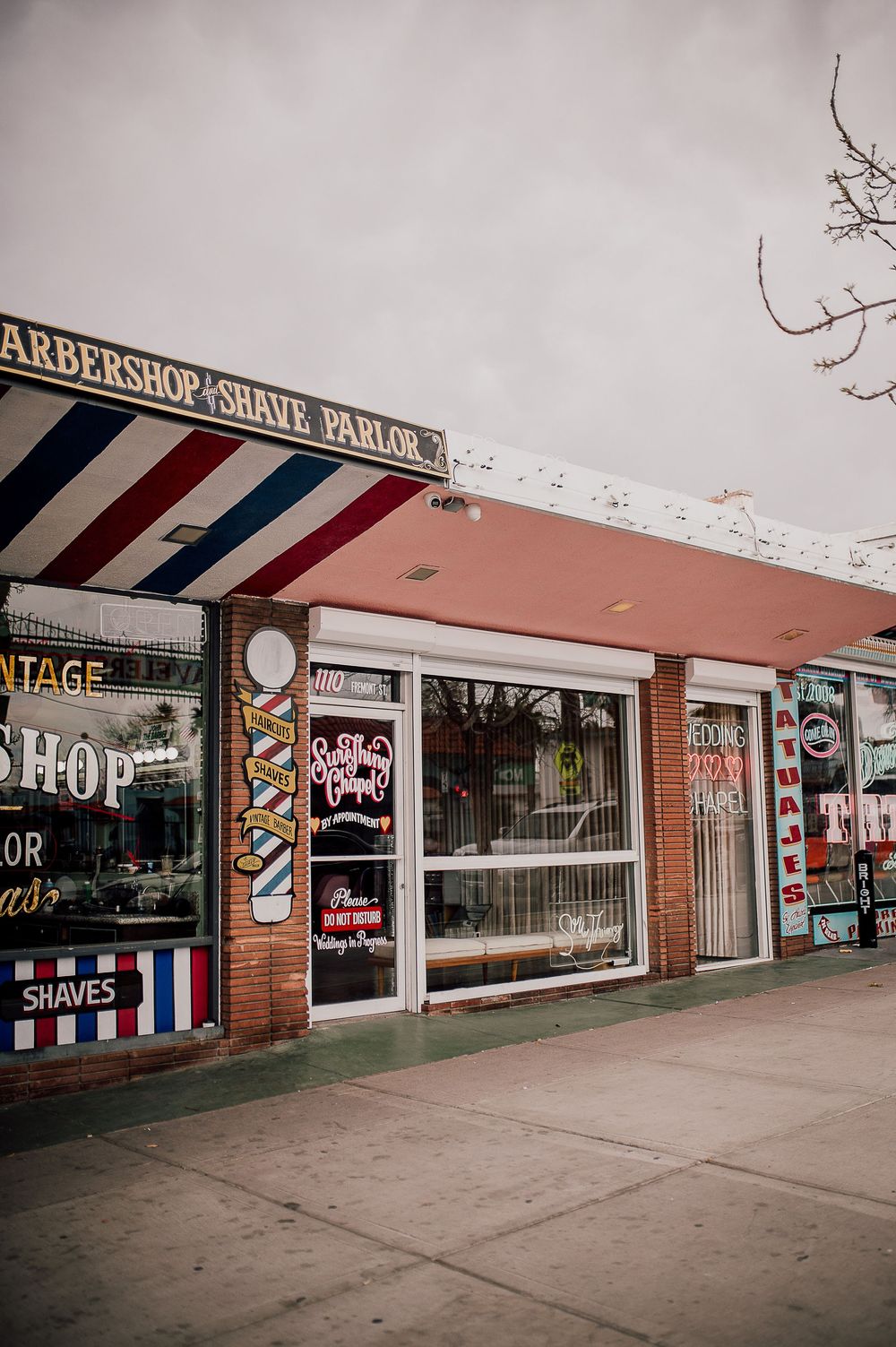Vintage barbershop storefront with classic red white and blue striped pole and retro signage on brick building exterior.