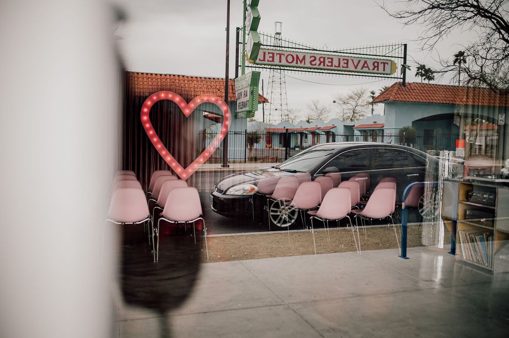 Neon heart light fixture and pink seating visible through window at Bottoms Up Pizza restaurant in Richmond, Virginia.