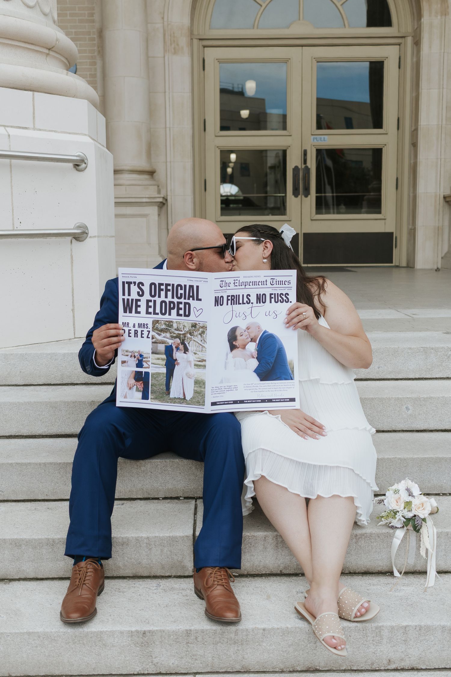 A playful elopement announcement photo on courthouse steps with a newspaper headline.