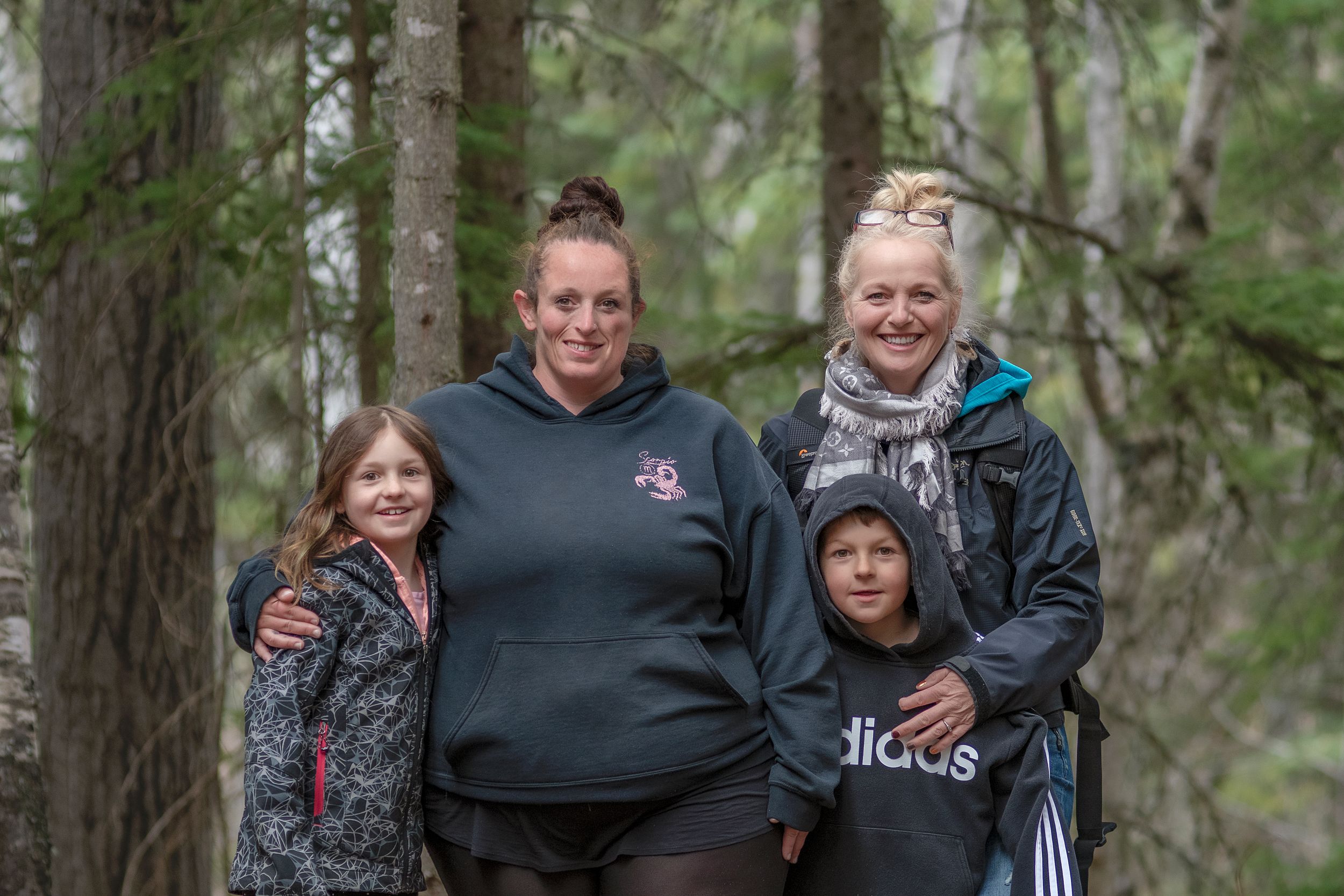Group of people enjoying a walk together in a lush green forest setting on a cloudy day.