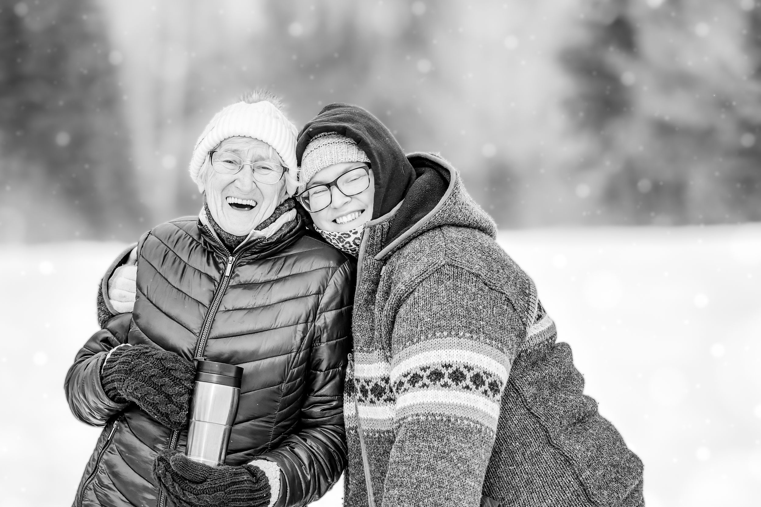 Two people share a joyful moment together in winter, wearing warm coats against a snowy background.