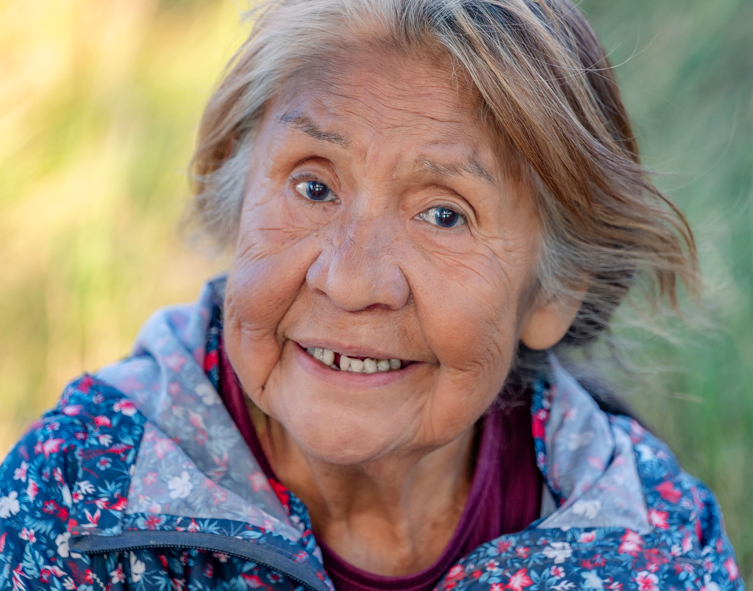 A series of five close-up portraits showing joyful expressions and warm smiles in natural outdoor lighting.