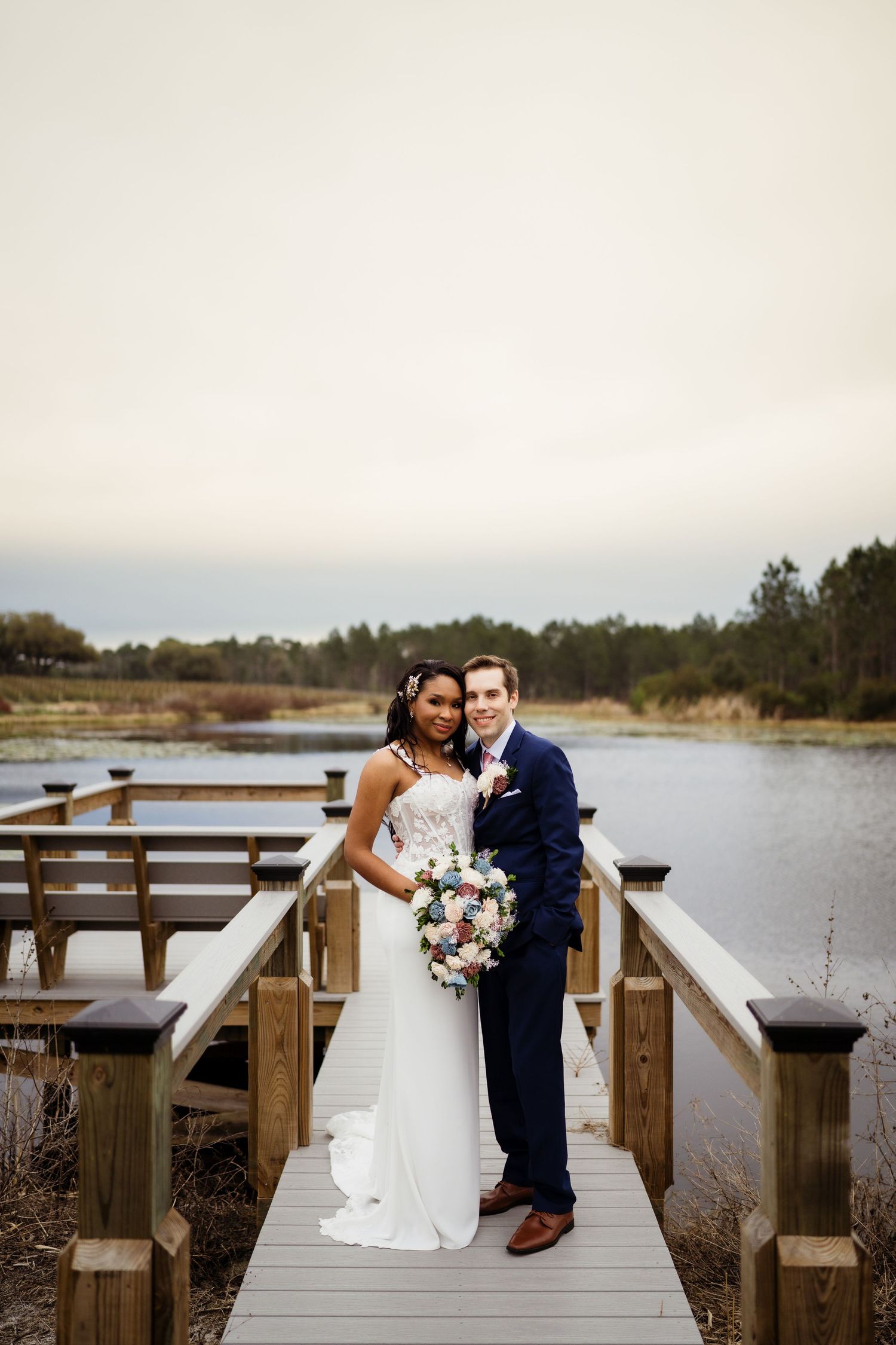 Couple shares intimate moments on a wooden dock overlooking a serene lake during their wedding photoshoot.