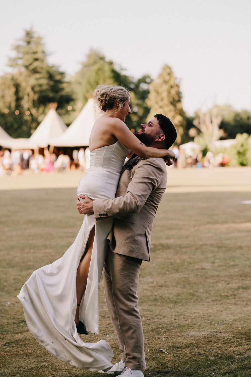 A couple shares a romantic dip-style dance pose in an outdoor field during golden hour.