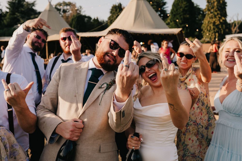 Wedding guests laughing and dancing together during an outdoor celebration in natural daylight.